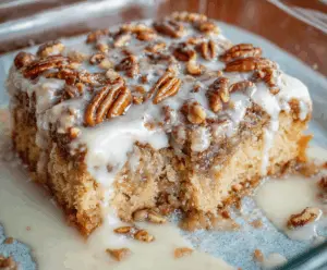 Delicious Butter Pecan Praline Poke Cake topped with whipped cream and toasted pecans, featuring a rich caramel and praline glaze for a sweet, nutty dessert